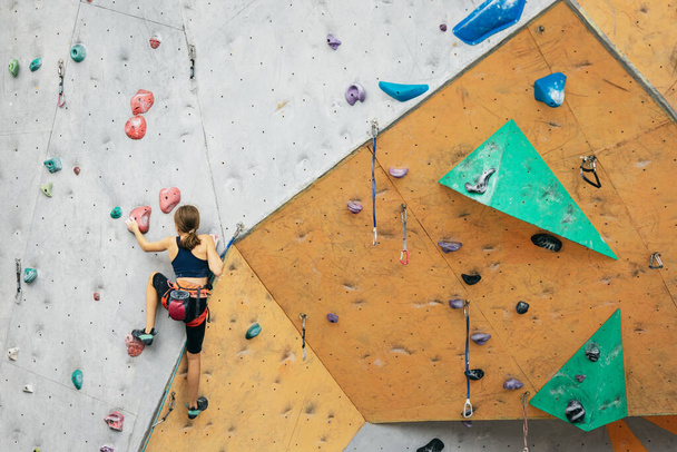 One cute teen girl practicing on the rock wall in climbing center. Concept of sportive lifestyle, activity, happy childhood - 写真・画像