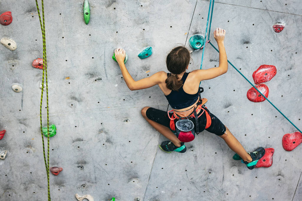 Одна милая девочка-подросток практикуется на скале в центре скалолазания. Концепция спортивного образа жизни, деятельности, счастливого детства - Фото, изображение