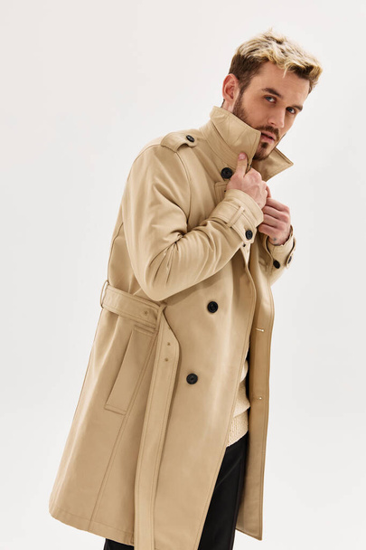 handsome man in beige coat posing in  studio. High quality photo - Photo, Image