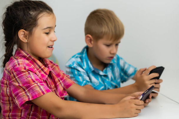 jongen spelen met smartphone naast zijn zus in de kamer thuis. - Foto, afbeelding