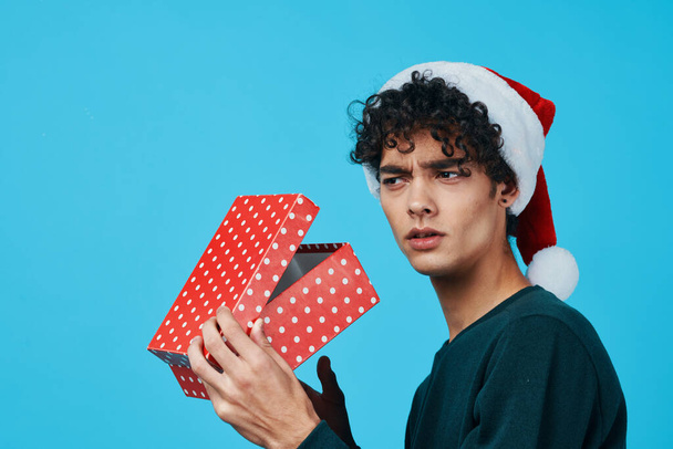 cute guy wearing santa hat gift on blue background. High quality photo - Photo, Image