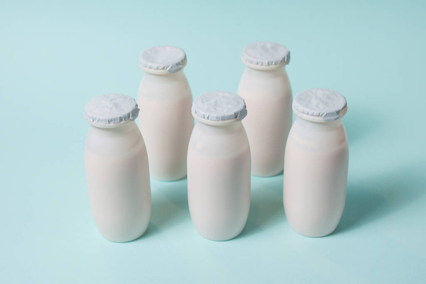 Bottles with probiotics and prebiotics dairy drink on light blue background. Bio yogurt with useful microorganisms. Production with biologically active additives. Fermentation and diet healthy food. - Foto, Imagen