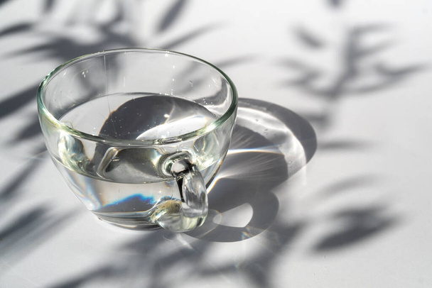 glass cup with water. Abstract shadow pattern on white background. Texture for the background. - Photo, Image
