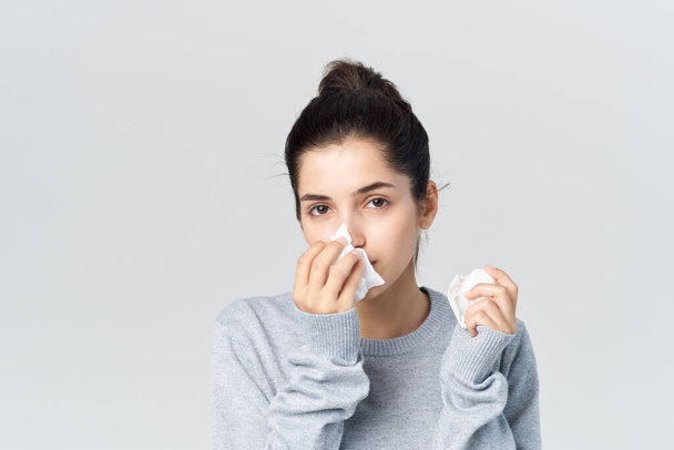 donna in maglione grigio si pulisce il viso con un fazzoletto, problemi di salute. Foto di alta qualità - Foto, immagini