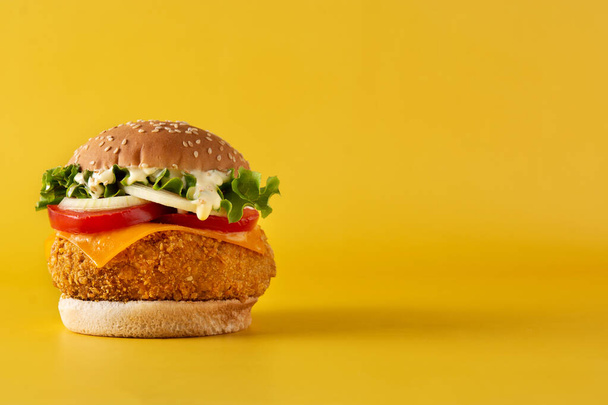Chrupiący hamburger z kurczakiem z serem na żółtym tle. Przestrzeń kopiowania - Zdjęcie, obraz