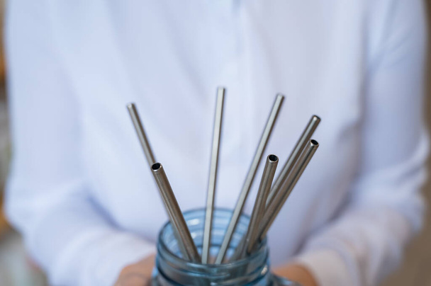 A woman holds a jar of reusable steel tubes. Eco concept - Foto, afbeelding