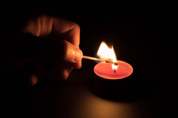 Lighting a red candle with a match in the dark. Memory concept. Black background. - Fotoğraf, Görsel