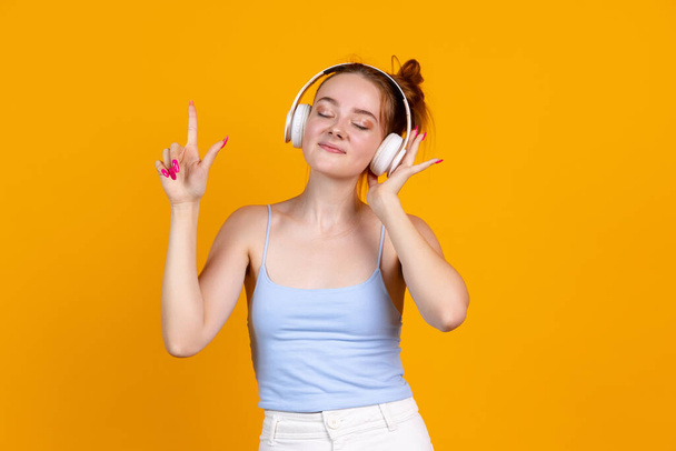 Portrait of pretty girl in headphones isolated on yellow studio background. Female fashion model in casual clothes. Concept of human emotions, natural beauty, youth - Fotografie, Obrázek