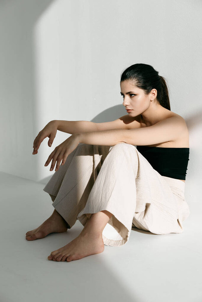barefoot woman in fashionable clothes sitting on the floor - Foto, imagen