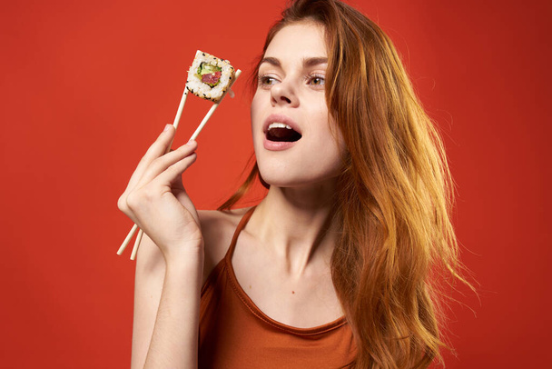 cute red-haired woman with chopsticks holding  roll - Fotografie, Obrázek