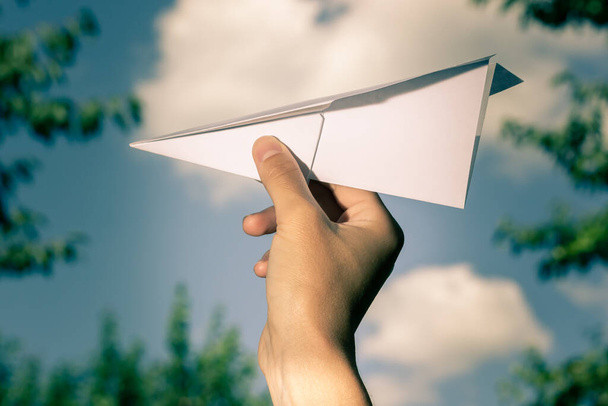 Paper plane in hand against the background of the sky. Origami. - 写真・画像