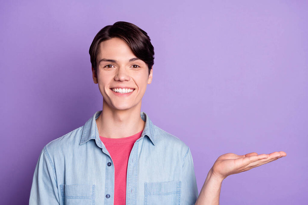 Fénykép a fiatal férfi boldog pozitív mosoly jelen termék ajánlat hirdetni elszigetelt felett lila színű háttér - Fotó, kép