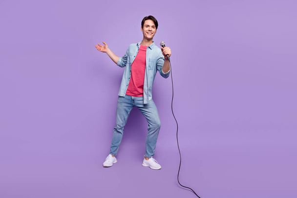 Full length photo of young man happy positive smile sing microphone karaoke isolated over purple color background - Фото, изображение