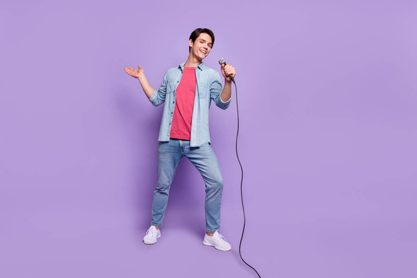 Full size photo of young man happy positive smile artist concert mic isolated over purple color background - Foto, afbeelding