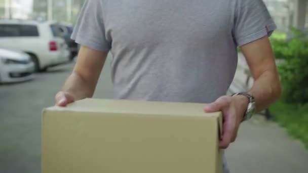 Ein Mann trägt eine Pappschachtel aus nächster Nähe die Straße hinunter - Filmmaterial, Video