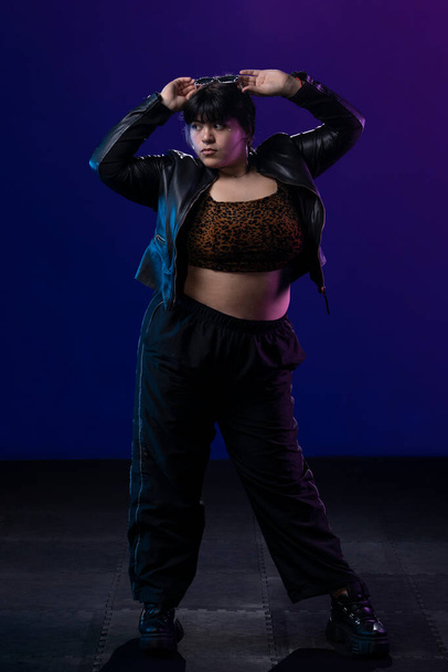 Portrait of a latin woman with pants and red cap, in a studio with blue background - Photo, image