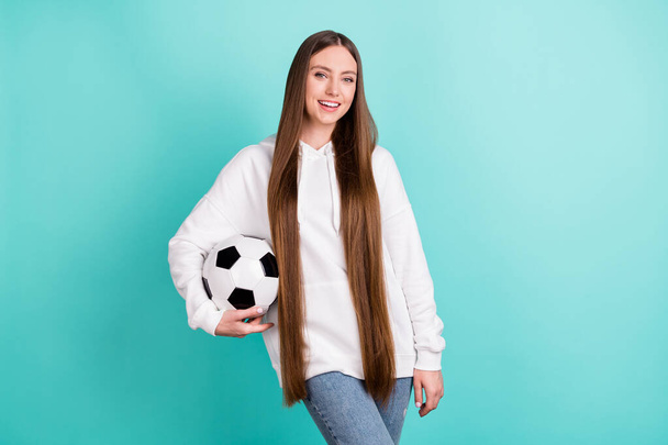 Photo of pretty charming young lady wear white sweatshirt holding football ball smiling isolated turquioise color background - Fotoğraf, Görsel