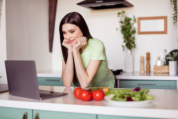Photo of lovely long hairdo young lady look laptop cook at kitchen wear green t-shirt at home alone - Foto, afbeelding