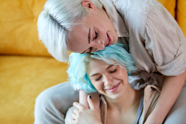 Happy Lesbian Couple Having Rest At Home Hugging On Sofa In Cozy Room - Foto, Bild
