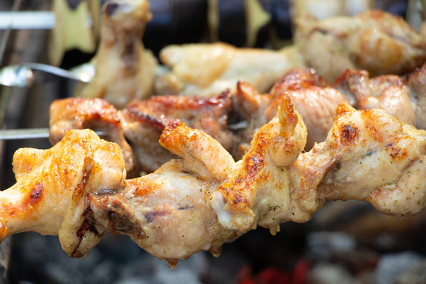 fried shish kebab on a fire in the forest on a picnic on skewers, roast shish kebab in nature, meat - Foto, imagen