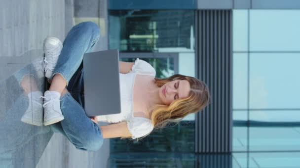 垂直ビデオ。若い魅力的な千年紀の女性は、キーボードを画面を見て入力するラップトップコンピュータを使用しています。幸せな自営業の女性は、電子メールで顧客の注文を受け、 OKジェスチャーを示しています. - 映像、動画