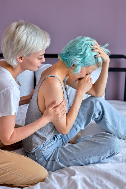 Caucasian lesbian couple trying to make up after argument on bed in bedroom - Fotoğraf, Görsel