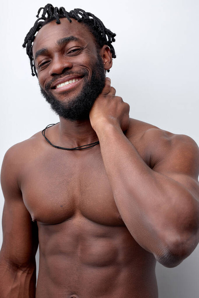 Optimistic shirtless guy with naked strong torso,muscular body touching neck, smiling - Valokuva, kuva