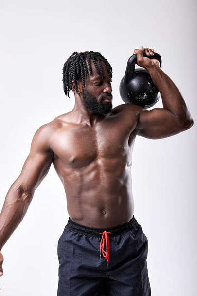 Portrait of strong young african man working out with kettle bell. Isolated white background - Fotografie, Obrázek