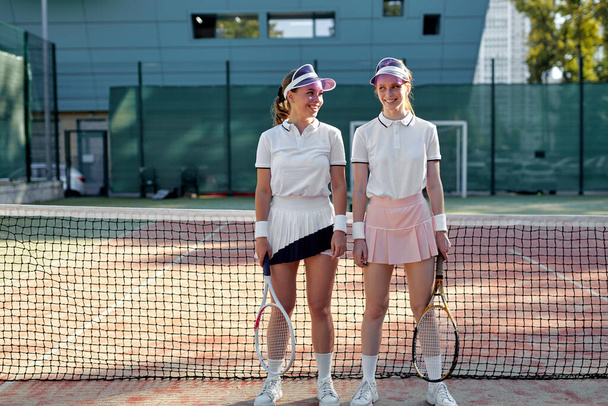 Sexy joyful women on court. Women in sports uniform with tennis racket ready to play - Foto, afbeelding