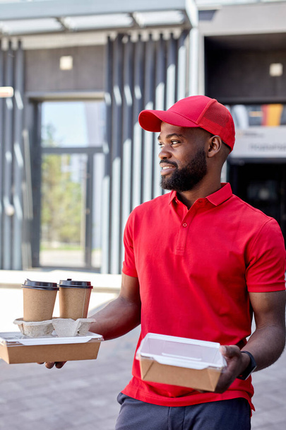 mensajero de entrega de alimentos que da cajas de comida y café, trabajador de café masculino para llevar al aire libre - Foto, Imagen