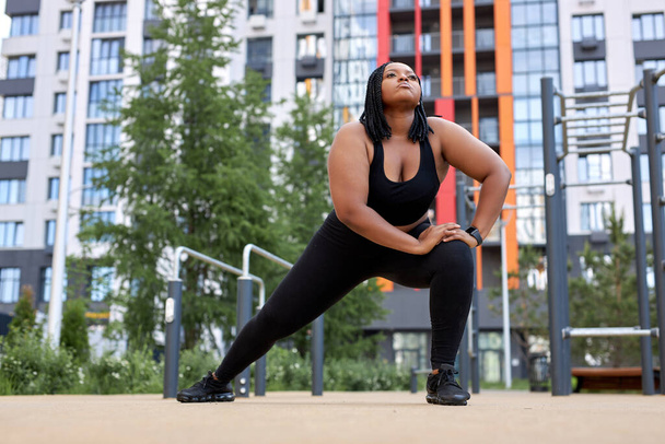 Concentrated afro american woman doing lunges in summer in city, training outdoors. - Foto, Imagem