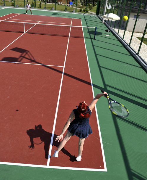 Young man play tennis outdoor on orange tennis court at early morning - 写真・画像