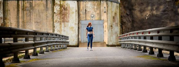 view from distance on young slim female walking on bridge alone outdoors - Φωτογραφία, εικόνα