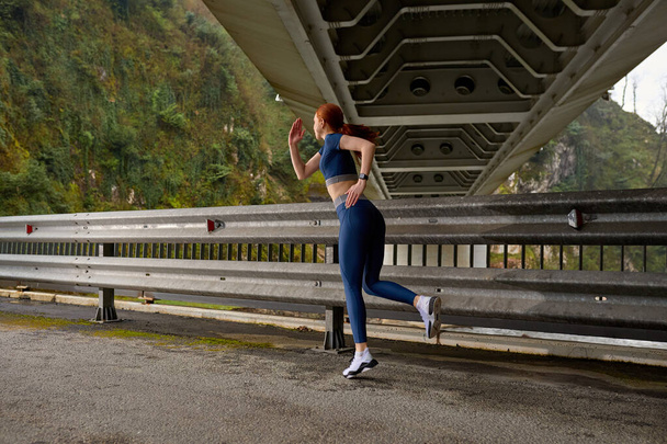 Fitness woman running jogging fast outdoors. Female athlete exercising on modern bridge. - Foto, Imagem