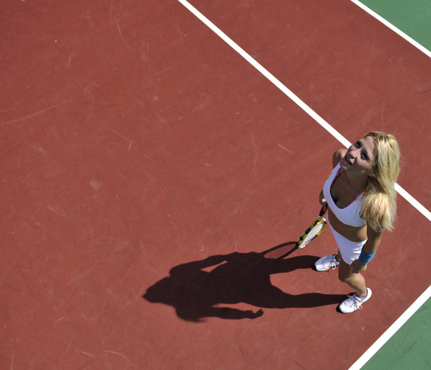 Young fit woman play tennis outdoor on orange tennis field at early morning - Foto, afbeelding