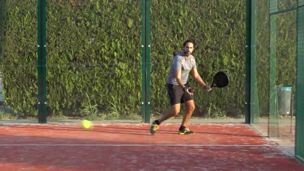 Trage beweging van een man die een paddle tennis techniek uitvoert tijdens een training of wedstrijd op een buitenbaan. - Video