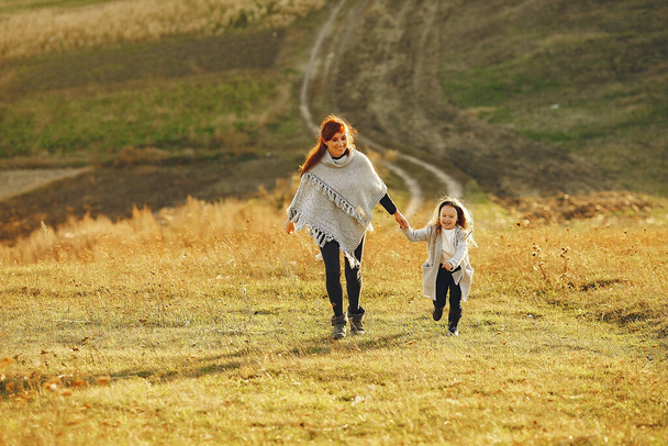 Mother with little daughter playing in a autumn field - Фото, зображення