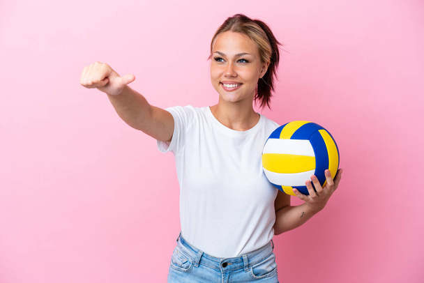 Young Russian woman playing volleyball isolated on pink background giving a thumbs up gesture - Photo, Image