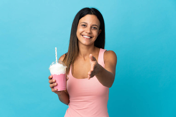 jonge vrouw met aardbei milkshake schudden handen voor het sluiten van een goede deal - Foto, afbeelding