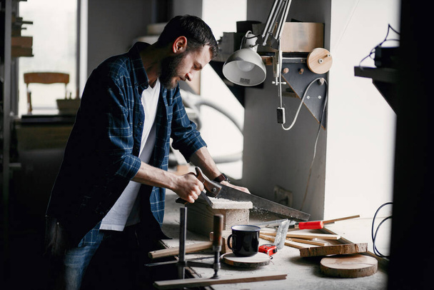 Hombre en el taller con una madera y sierra - Foto, Imagen