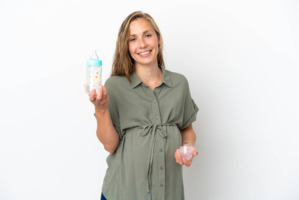 Молода біла жінка ізольована на білому тлі вагітна і тримає пляшку для годування
 - Фото, зображення