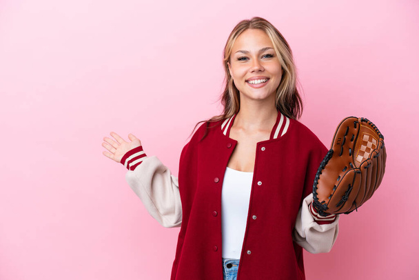 Player Russian woman with baseball glove isolated on pink background extending hands to the side for inviting to come - Foto, imagen