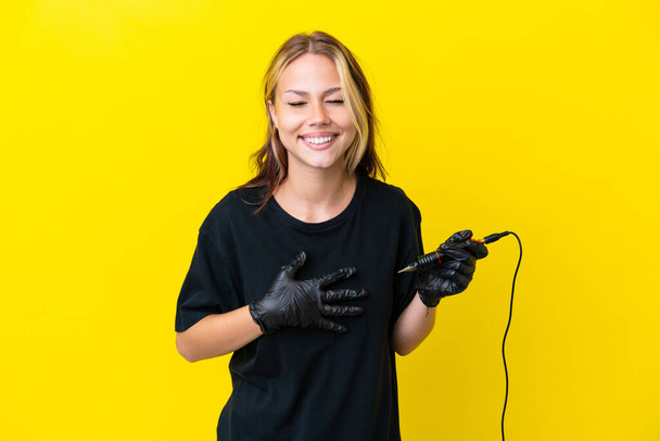 Tattoo artist Russian woman isolated on yellow background smiling a lot - Photo, Image