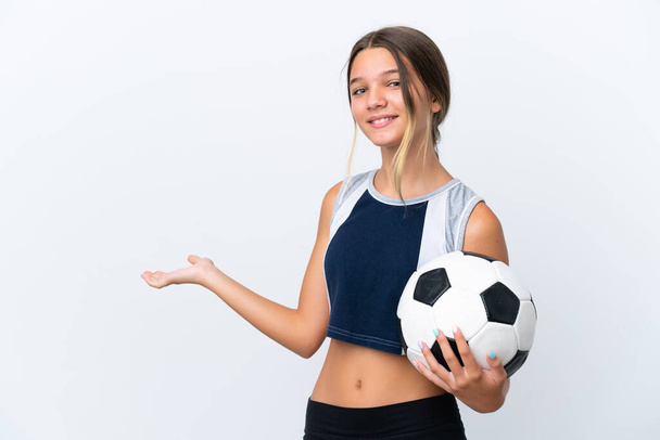 Kleines kaukasisches Mädchen, das isoliert auf weißem Hintergrund Fußball spielt und die Hände zur Seite ausstreckt, um zum Kommen einzuladen - Foto, Bild