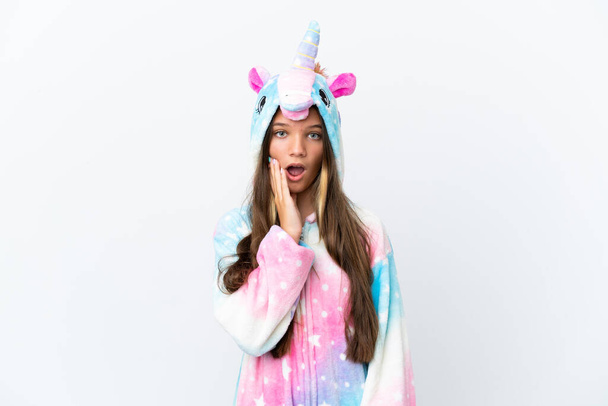 Little caucasian girl wearing unicorn pajama isolated on white background surprised and shocked while looking right - Photo, image