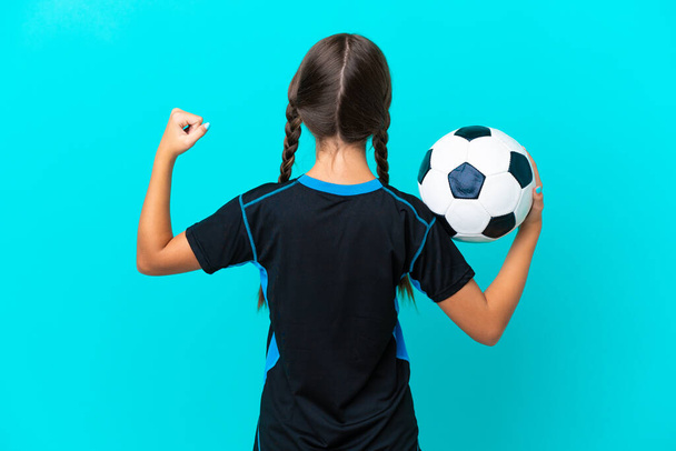 Little caucasian girl isolated on blue background with soccer ball - Photo, Image