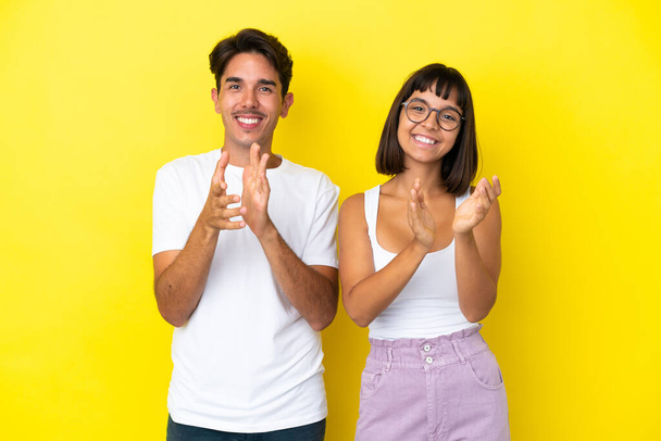 Giovane coppia mista isolato su sfondo giallo applaudendo dopo la presentazione in una conferenza - Foto, immagini