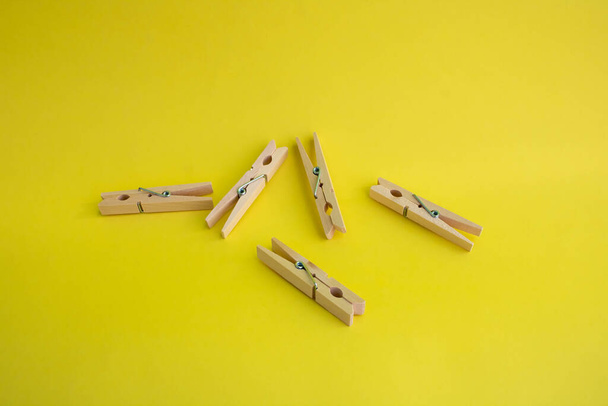 Wooden clothespins for drying clothes on a yellow background. - Zdjęcie, obraz