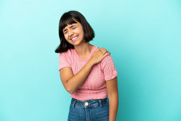 Young mixed race woman isolated on blue background suffering from pain in shoulder for having made an effort - Фото, изображение