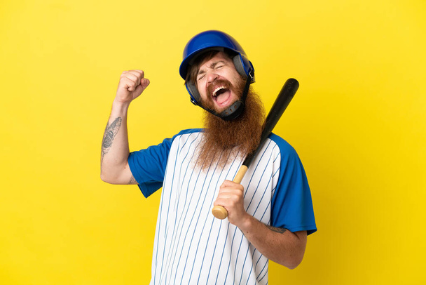 Рудий бейсболіст чоловік з шоломом і кажаном ізольований на жовтому тлі, що святкує перемогу
 - Фото, зображення